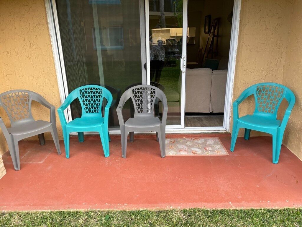 Un patio con tres sillas y un gran ventanal corredizo que da a un espacio interior.