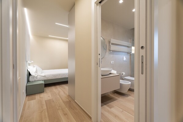 Une chambre à coucher moderne et compacte, dotée d’un lit simple, d’une petite table de chevet et d’une armoire intégrée.