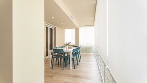 A modern dining area with a white table and teal chairs, a potted plant, and a view of the outdoors. - Miramare by Monholiday (Monopoli)