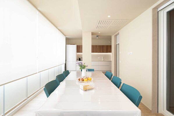 A modern dining area with a long table, teal chairs, and a tray with food and drinks.