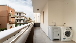 A balcony with a washing machine and a sink, overlooking a residential area. - Miramare by Monholiday (Monopoli)