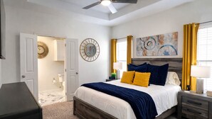 A bedroom with a bed, bedside tables, a ceiling fan, and artwork on the wall. - 2BR Townhome • EV Charger • Near Texas A&M (College Station)
