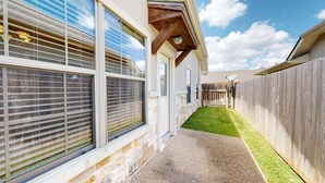 A narrow pathway leading to a house with large windows and a wooden fence. - 2BR Townhome • EV Charger • Near Texas A&M (College Station)