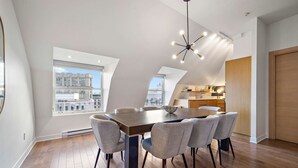 Un'area pranzo moderna con un tavolo grande, sei sedie e vista sulla città attraverso un'ampia finestra.