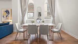 Un'area pranzo moderna con un tavolo bianco, quattro sedie grigie e un grande specchio sopra.