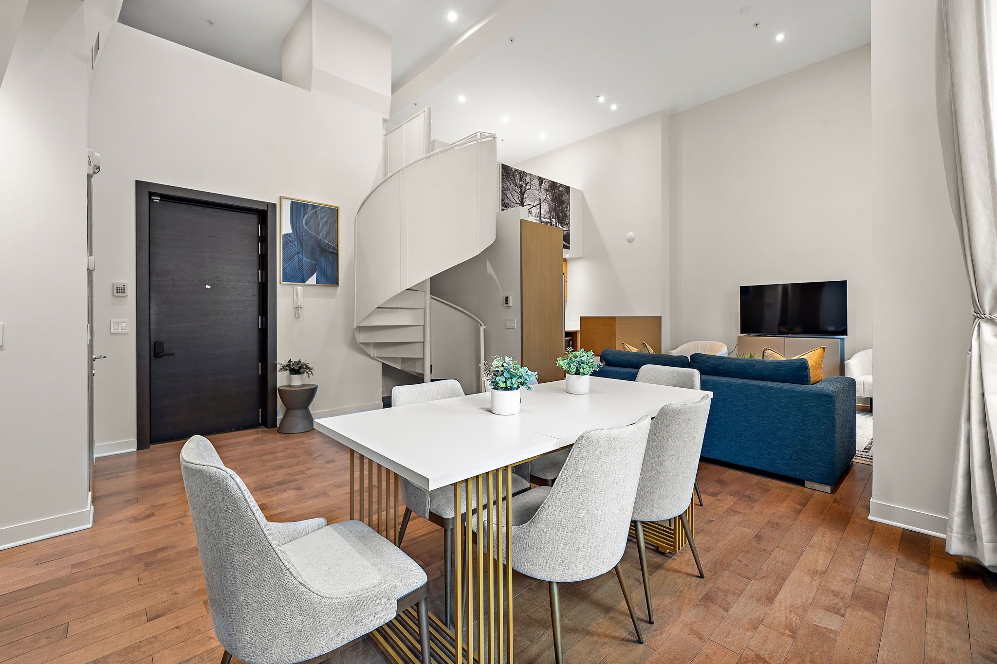 Un appartement moderne comprenant un coin repas, un salon et un escalier.