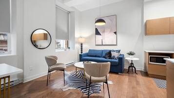 A modern living room with a blue sofa, two armchairs, a round coffee table, a zebra rug, and a contemporary art piece.