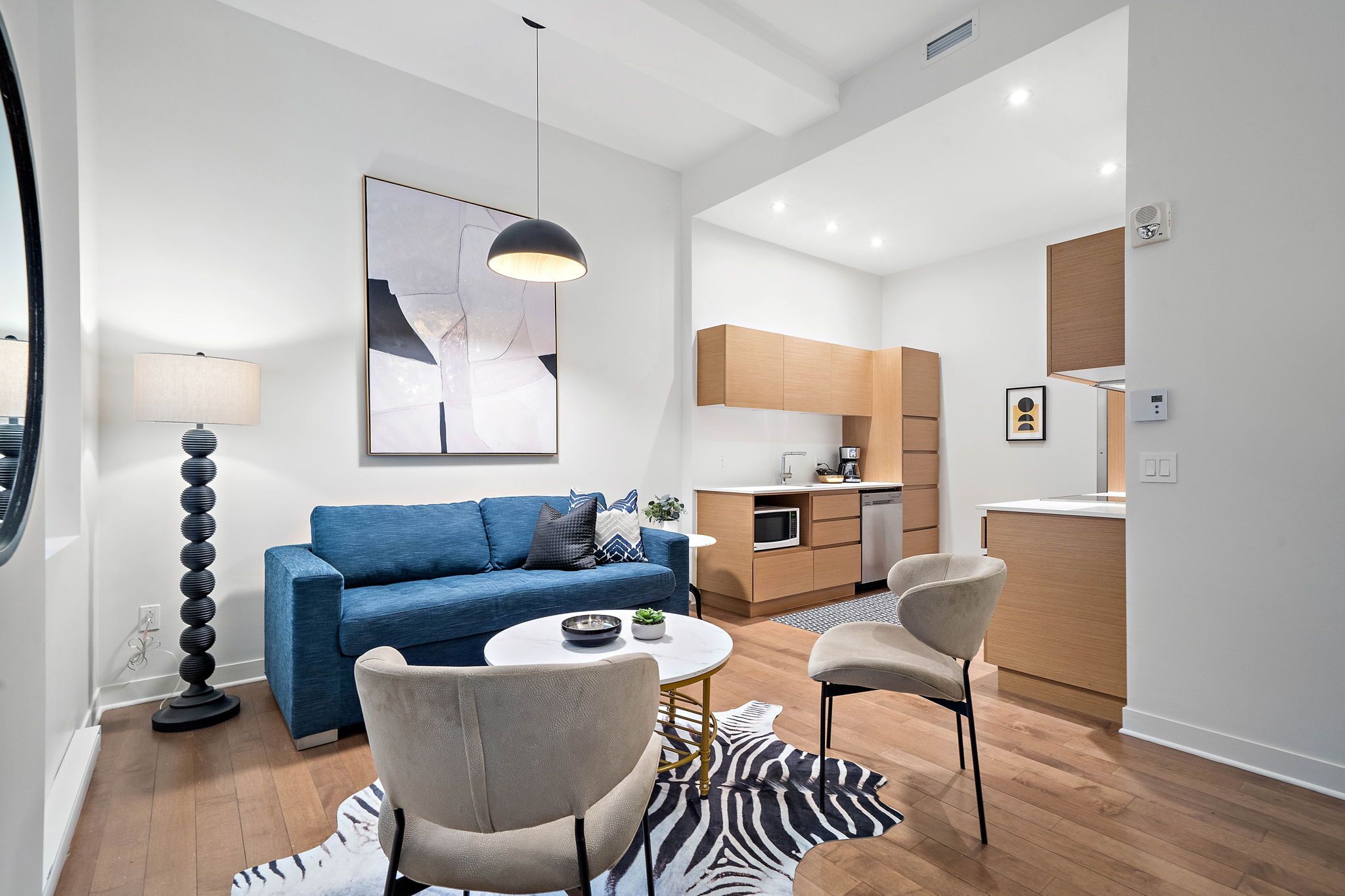 Een moderne woonkamer met een blauwe bank, een ronde salontafel en een vloerkleed met zebraprint.