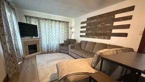 A living room with a sofa, a coffee table, a TV, and a fireplace.