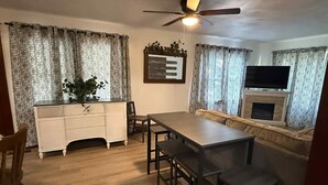 A dining area with a wooden table and chairs, a white cabinet, and a ceiling fan.