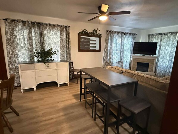 A dining area with a wooden table and chairs, a white cabinet, and a ceiling fan.