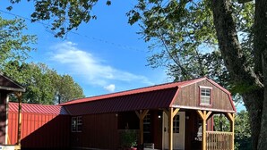 Ein rot gestrichenes Bauernhaus mit Veranda und Treppen zum Eingang.