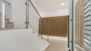 Un interior moderno con una escalera, barandillas de vidrio y un panel de pared de madera.