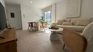 Una sala moderna con un sofá, una mesa de comedor con sillas, una mesa de centro y un mueble para la televisión.