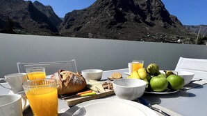 Desayuno con vistas a la montaña, que incluye platos, vasos y diferentes opciones de comida.