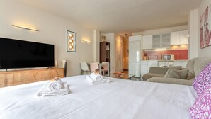A hotel room with a bed, a TV, a kitchenette, and a dining area. - Exclusive Beachfront Apartment. (Costa Adeje)