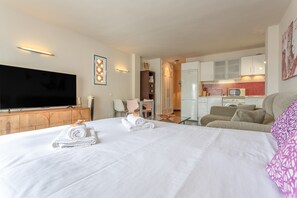 A hotel room with a bed, a TV, a kitchenette, and a dining area.