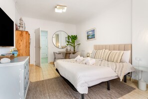 A bedroom with a bed, bedside table, TV, and a plant.