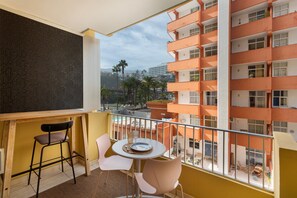 A balcony with a table, chairs, and a view of a multi-story building.