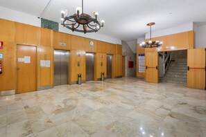 A lobby with wooden paneling, a marble floor, and a staircase leading to an upper level.