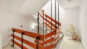 Ein modernes Interieur mit einer Holztreppe, einem Topfpflanzen und einer weißen, hellen Wand.