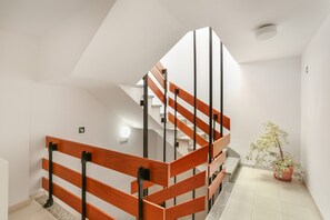 Un intérieur moderne avec un escalier en bois, une plante en pot et un mur blanc et épuré.