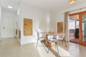 Un espace repas moderne avec une table ronde, quatre chaises et deux œuvres d’art abstraites accrochées au mur.