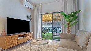 A living room with a flat-screen TV, a sofa, a coffee table, and a large plant.