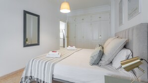 A bedroom with a bed, bedside lamp, and a mirror.