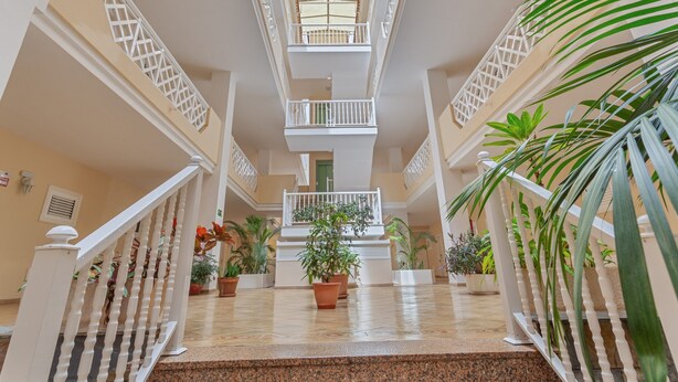A multi-level atrium with a central staircase, potted plants, and a glass ceiling.