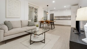 Ein modernes Wohnzimmer mit Sofa, Couchtisch und Essbereich.