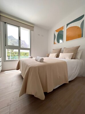 Une chambre à coucher avec un lit, une fenêtre et des œuvres d’art abstraites accrochées au mur.