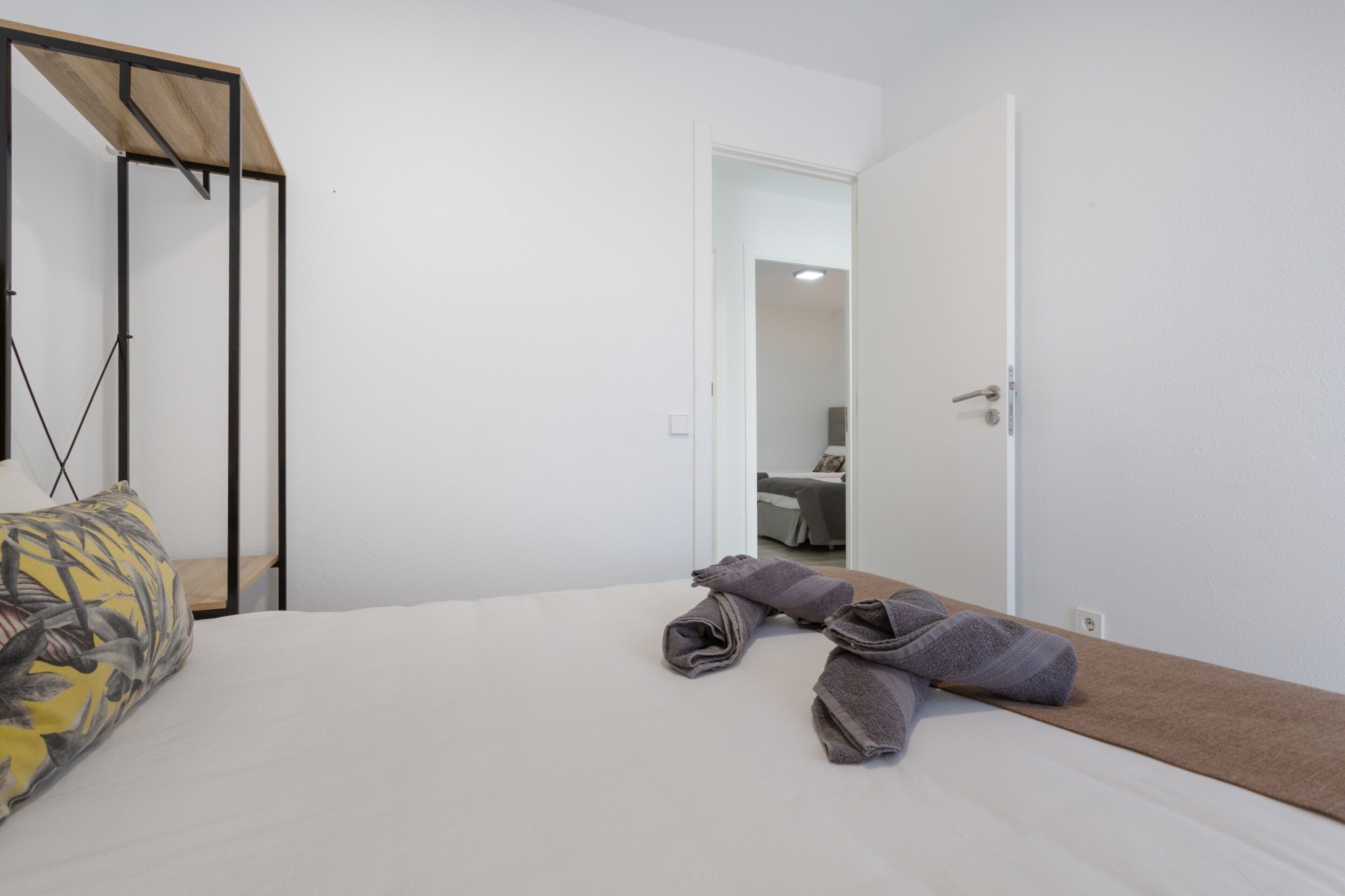 A hotel room with a bed, a wooden headboard, a door, and a small table with towels.