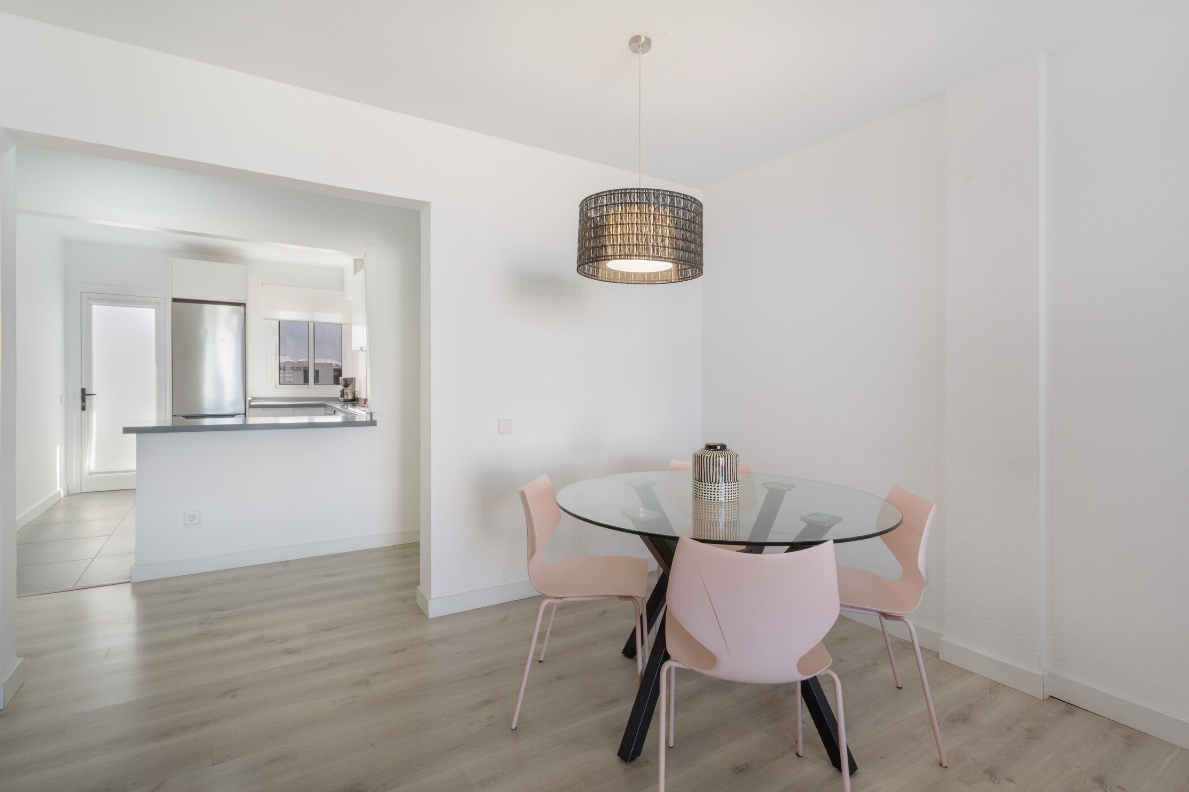 A modern kitchen with a stainless steel refrigerator, a glass island, and a hanging pendant light.