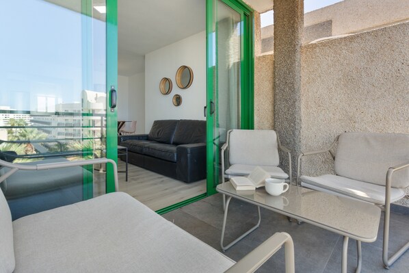 A modern living room with a glass door leading to a balcony, a sofa, a coffee table, and a view of the city.