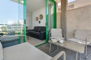 A modern living room with a glass door leading to a balcony, a sofa, a coffee table, and a view of the city.