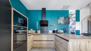 Une cuisine moderne dotée d’un îlot central, d’un four encastré et d’une hotte noire.