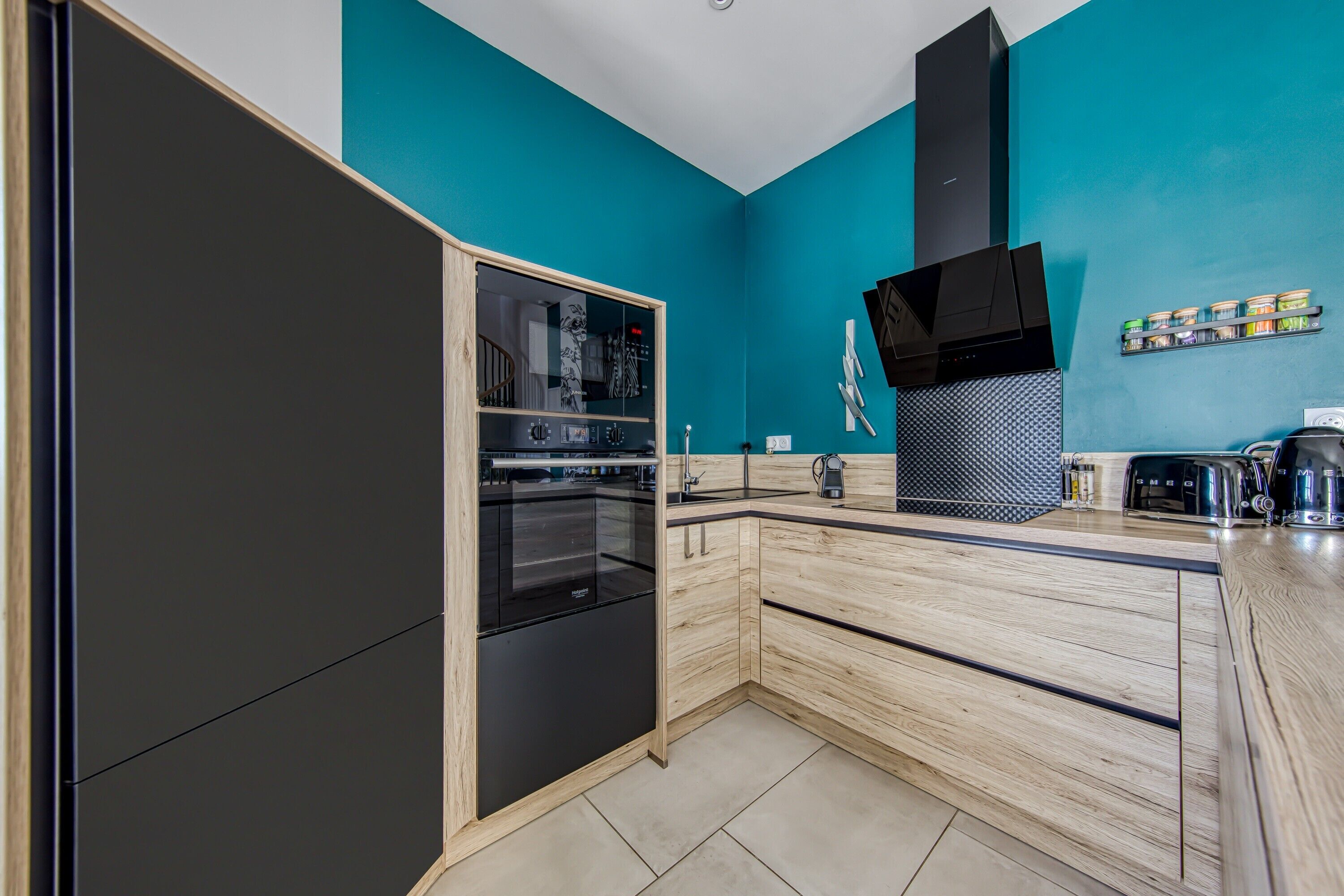 Una cocina moderna con horno integrado, extractor de aire negro y encimera de madera.
