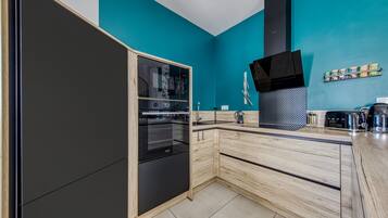 Una cocina moderna con horno integrado, extractor de aire negro y encimera de madera.