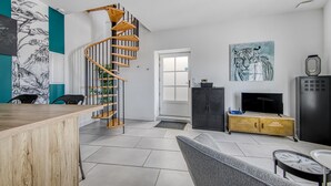 Un intérieur moderne avec un escalier en colimaçon, un téléviseur, un meuble et un tableau représentant un tigre.