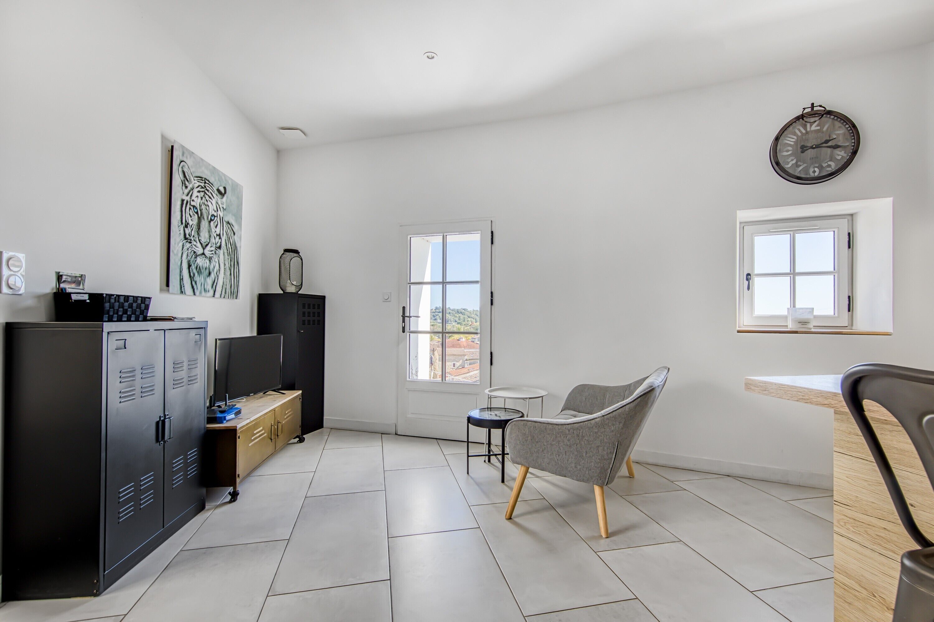 A modern room with a large cabinet, a chair, a small table, and a wall clock.