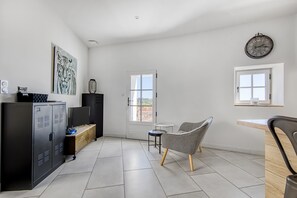 Ein modernes Zimmer mit einem großen Schrank, einem Sessel, einem kleinen Tisch und einer Wanduhr.