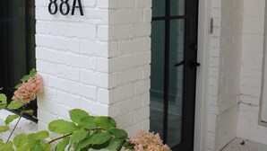 Un edificio de ladrillo blanco con una puerta negra y un letrero con el número '88A'.