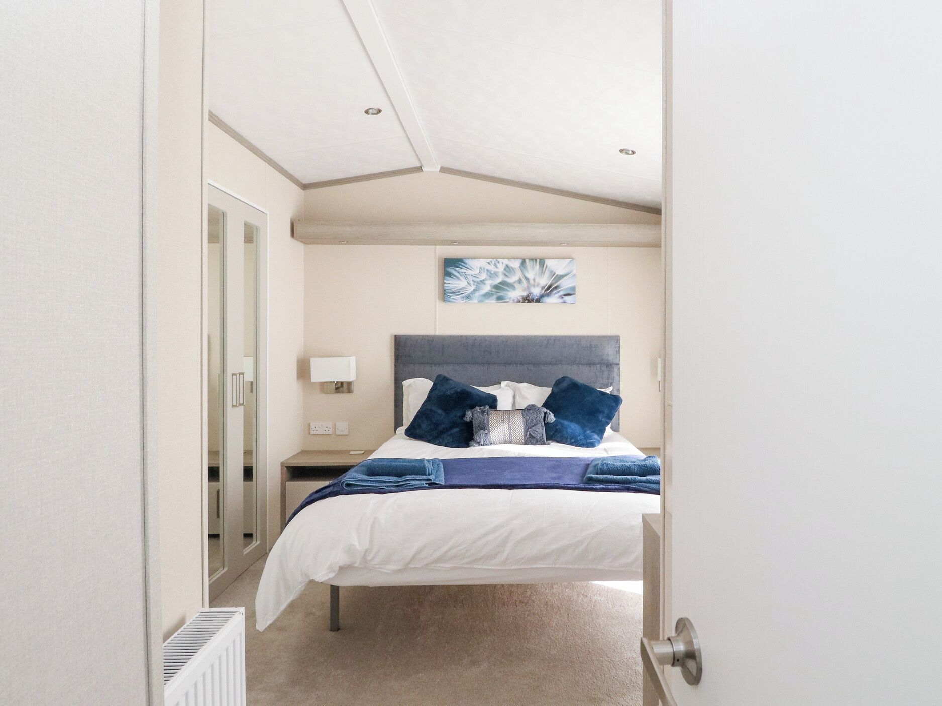 A bedroom with a bed, a nightstand, a wall-mounted lamp, and a ceiling light.