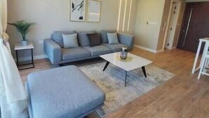 En moderne stue med en grå sofa, et hvidt sofabord og trægulv.