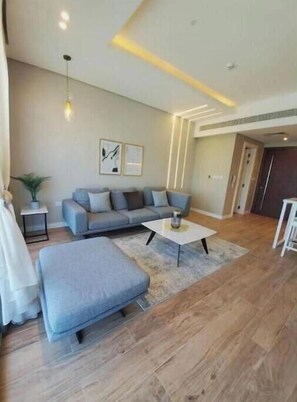 Un salon moderne avec un canapé gris, une table basse blanche et un plancher en bois.