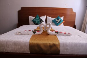 Ein ordentlich bezogenes Bett mit goldfarbener Tagesdecke, zwei schwanenförmigen Handtüchern und Zierkissen.