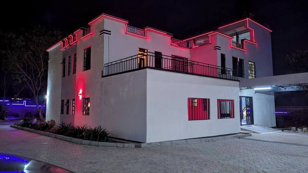 Um edifício moderno com fachada branca e detalhes vermelhos, apresentando uma varanda e portão.