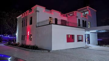 Um edifício moderno com fachada branca e detalhes vermelhos, apresentando uma varanda e portão.