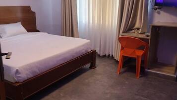 Una habitación de hotel con cama, escritorio y televisor.